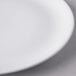 A close-up of a Libbey white porcelain coupe plate with a white rim.