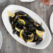 A platter of mussels and lemon wedges with a shell on a lemon slice.