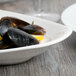 A table set with a bowl of mussels and lemon slices on a white Libbey porcelain handle platter.