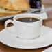 A Libbey white espresso cup on a saucer with coffee.