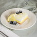 A Tuxton Hampshire china bread and butter plate with lemon cake and blueberries on it.