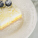 A Tuxton Hampshire eggshell embossed china bread and butter plate with a piece of lemon cake topped with blueberries.