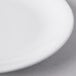 A close up of a Libbey white porcelain coupe plate with a white rim on a gray surface.