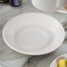A Tuxton Hampshire eggshell embossed white saucer on a white marble table.