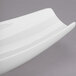 A white porcelain canoe plate with a curved edge.