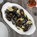 A Libbey white porcelain oval platter with mussels and lemon slices.
