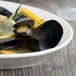 A bowl of mussels and lemon slices served on a Libbey Royal Rideau white porcelain platter.