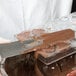 A person using a spatula to spread chocolate into a Matfer Bourgeat chocolate mold.