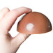 A hand holding a chocolate dome.