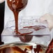 A person pouring chocolate into a Martellato polycarbonate mold.
