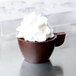 A close up of a chocolate cup made with a Martellato polycarbonate chocolate mold with whipped cream on top.
