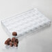 A clear plastic Martellato chocolate mold tray with oval compartments filled with chocolates.