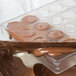 A Chocolate World 32-compartment chocolate mold being filled with chocolate.