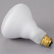 A white Satco BR30 light bulb with a gold base on a gray surface.