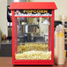 A red Satco BR30 flood light illuminating a red popcorn machine with a bowl of popcorn in it.