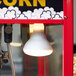 A Satco frosted shatterproof flood light bulb on a popcorn machine.