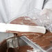 A person pouring liquid chocolate into a Matfer Bourgeat plastic chocolate mold.