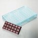 A Matfer Bourgeat plastic tray with square shapes filled with chocolate bars.