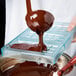 Liquid chocolate being poured into a Matfer Bourgeat chocolate mold with three compartments.