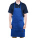 A man wearing a royal blue Chef Revival bib apron with one pocket.