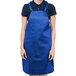 A woman wearing a royal blue Chef Revival bib apron.