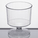 A clear plastic pedestal wine cup on a white surface.