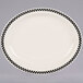An ivory narrow rim oval platter with black and white checkered trim.