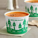 A bowl of soup in a white and green EcoChoice Compostable paper food cup with a tree design.
