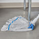 A Unger SmartColor blue and white microfiber string mop head on the floor.