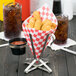 A Clipper Mill stainless steel fry cone stand with a basket of tater tots on a table.
