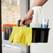 A hand holding Rubbermaid Deluxe Janitorial Cleaning supplies in a black container.