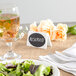 A table setting with Choice oval vinyl chalkboard labels on a plate of salad and a glass of drink.