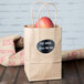 A brown paper bag with a vinyl chalkboard label on it with the word "apple" written on it.