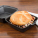 A sandwich in a small black foam hinged lid container.