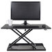 A black Luxor stand up desktop desk with a computer monitor and keyboard on it.