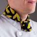 A man wearing a corn patterned chef neckerchief on a counter in a professional kitchen.