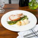 A Homer Laughlin bright white china plate with meat and asparagus on it.