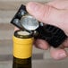 A hand using a Franmara black wine foil cutter to open a bottle of wine.