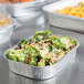 A Durable Packaging mini foil pan with broccoli and carrot salad.