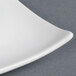 A close-up of a white CAC China divided tasting plate with a curved edge.