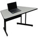 A laptop on a Correll gray granite melamine top trapezoid desk.