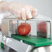 A person in gloves using a Garde tomato slicer to cut a tomato.