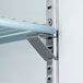 A metal shelf with a metal bar on a metal corner inside an Avantco reach-in freezer.