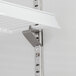 A white metal shelf with a metal bracket attached to it.