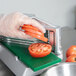A person in gloves using a Garde tomato slicer to cut tomatoes.