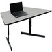 A black laptop on a gray granite Correll table with a trapezoid shape.