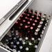 An Avantco stainless steel horizontal bottle cooler on a counter filled with beer bottles.