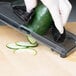 A person using a Mercer Culinary hand slicer blade to cut cucumbers on a counter.