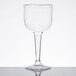 A Fineline clear plastic wine goblet with a long stem on a table.