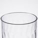 A close up of a clear Fineline Flairware plastic wine goblet with a wavy rim.